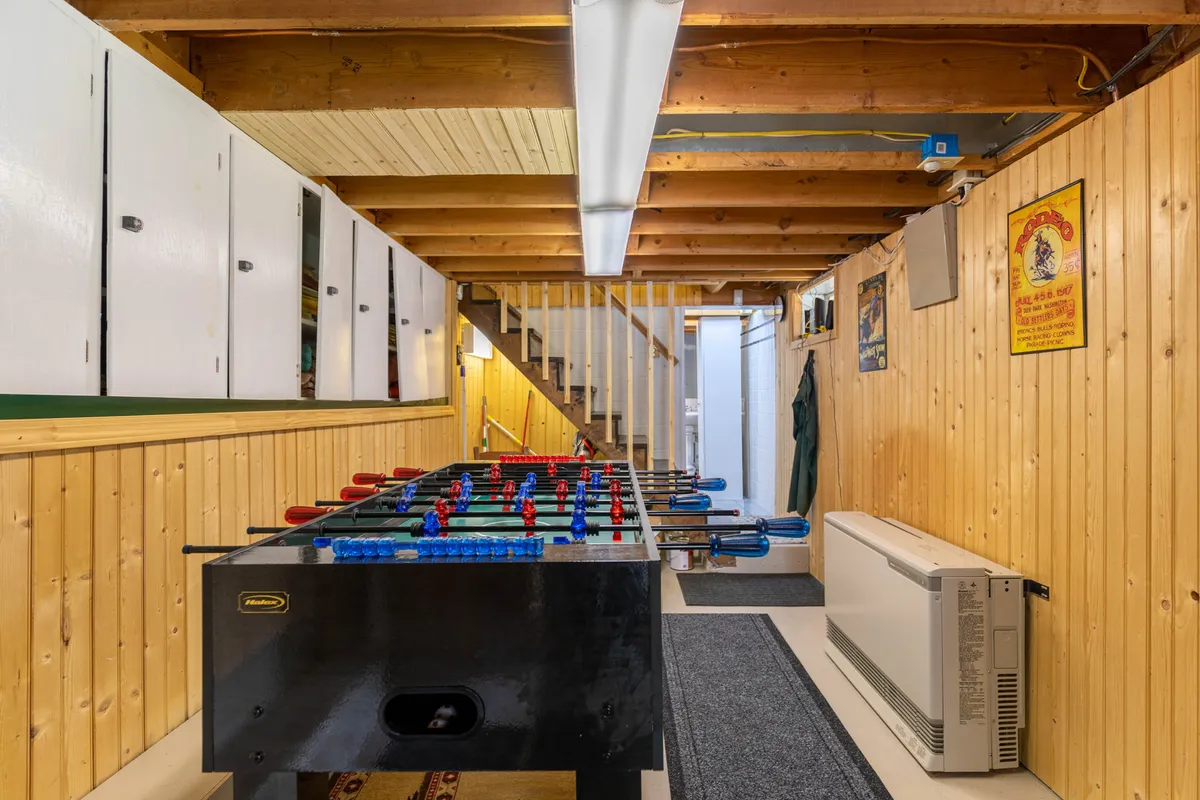 This interior image captures the lively game room, with a foosball table, cozy wooden paneling, and colorful posters. The inviting space is designed for family fun and friendly competitions, rounding out the adventure theme with an all-weather bonding activity.