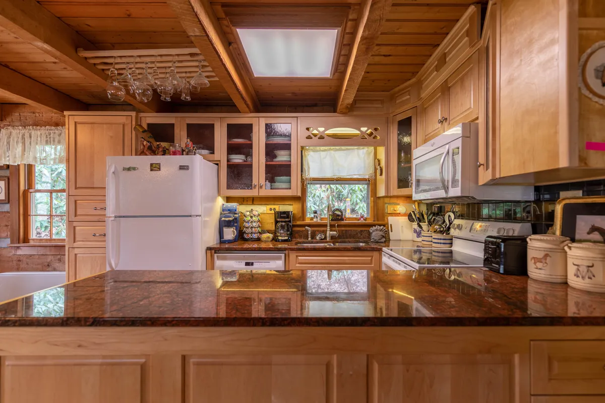 A closer interior shot of the kitchen area featuring granite countertops, wooden cabinets, a large window letting in natural light, and modern appliances. The space looks ready for meal preparation and easy cleanup, aligning with the section's emphasis on the fully equipped kitchen and dishwasher.